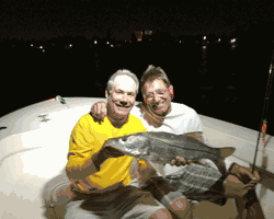 two men on a boat holding a large fish
