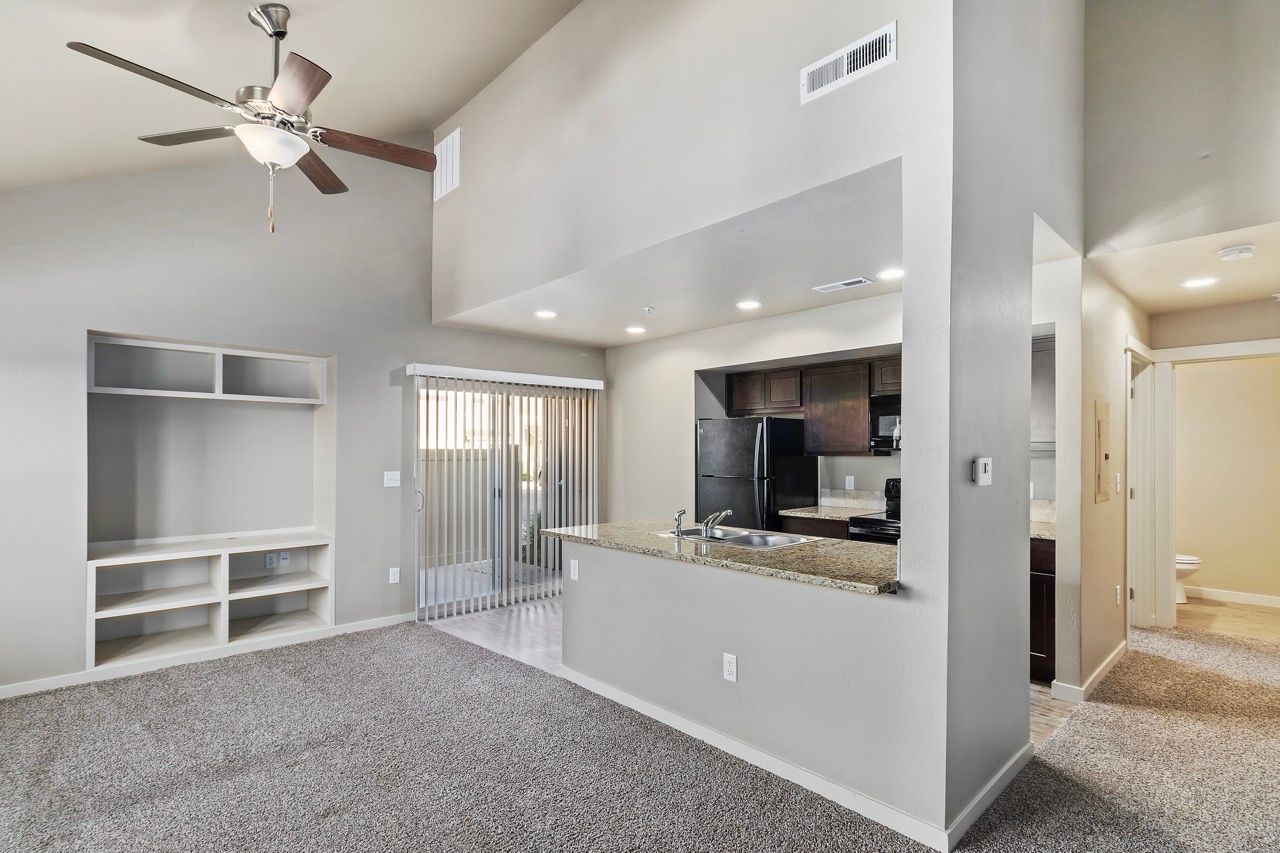 Open-concept living area with kitchen island, granite countertops, and sliding door to the patio.