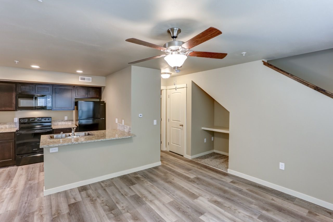 Open-concept kitchen with granite island, dark cabinets, and laminate flooring.