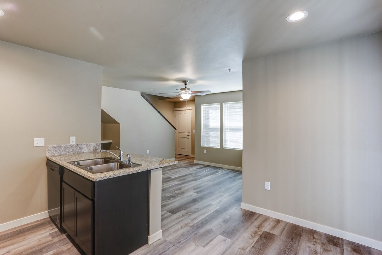 Open-concept apartment kitchen with granite island, sink, and adjacent living area.