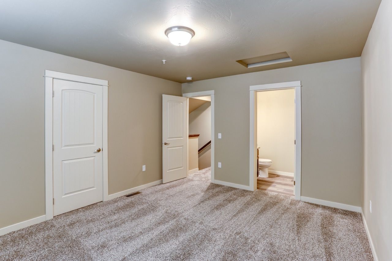 Interior room with beige walls, white trim, carpet, and three doorways.