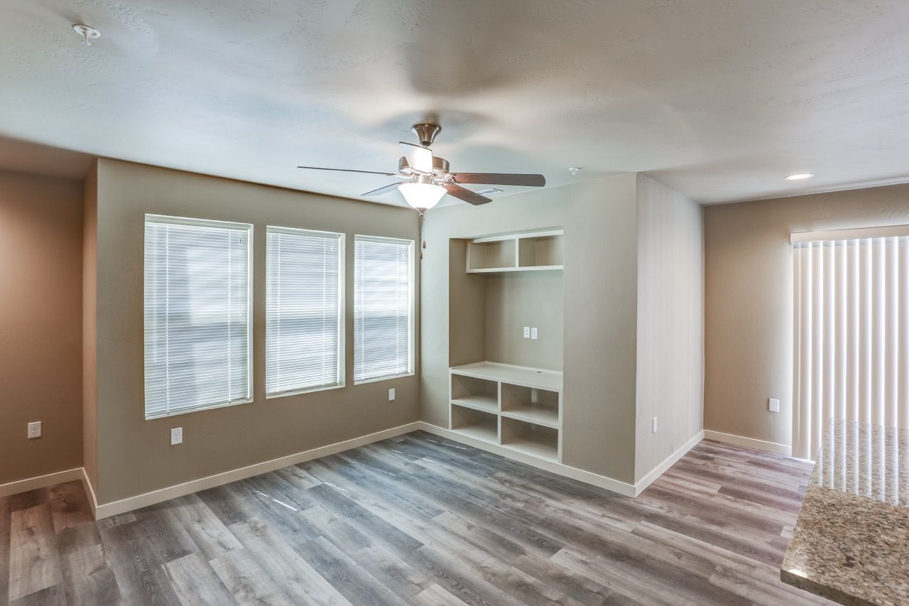 Living room with three large windows, built-in shelves, and a ceiling fan.