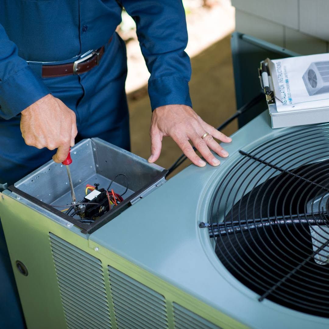 HVAC technician inspecting an outdoor air conditioner during spring maintenance
