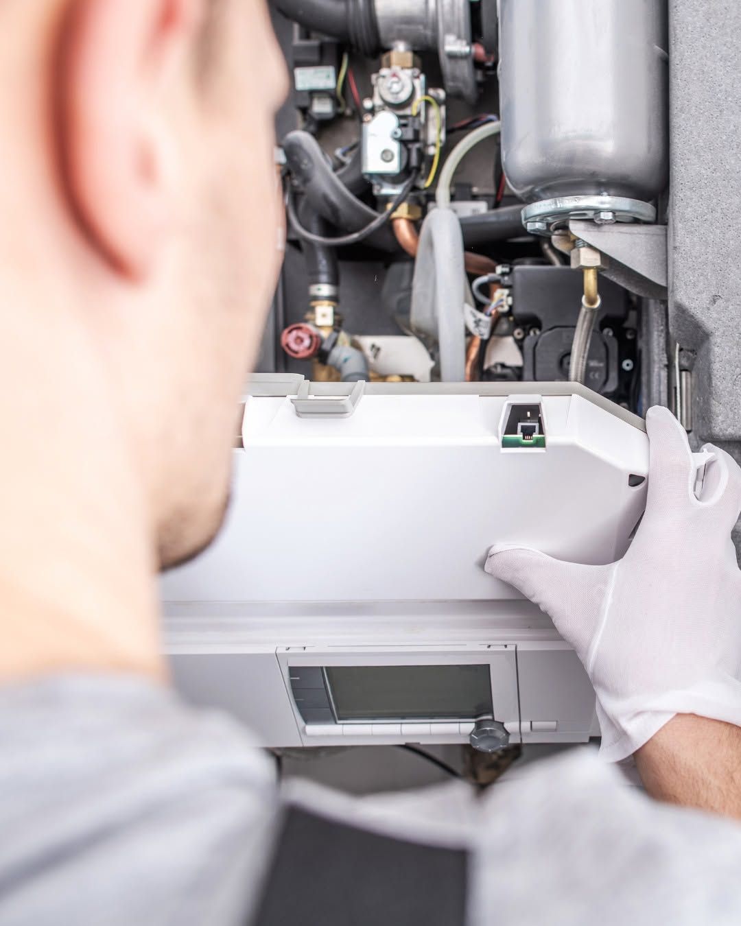 Technician installing a white device inside an open electrical or HVAC unit