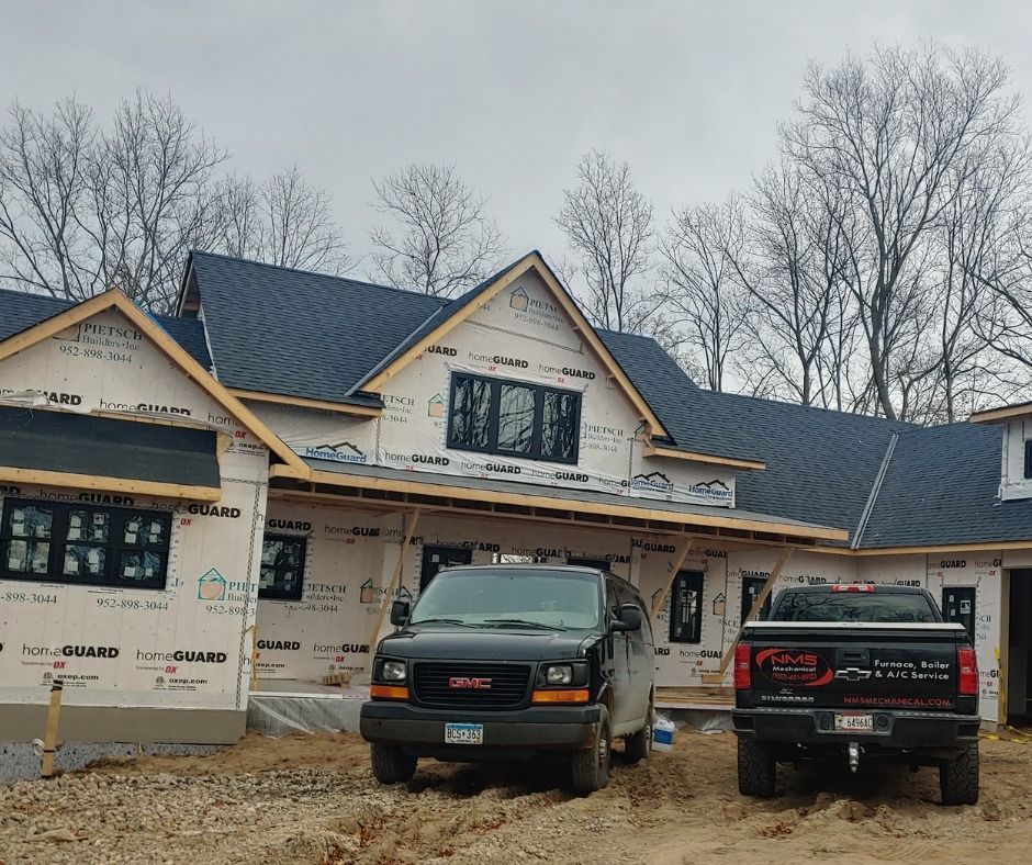 Partially finished house with two black pickup trucks parked in front under overcast skies