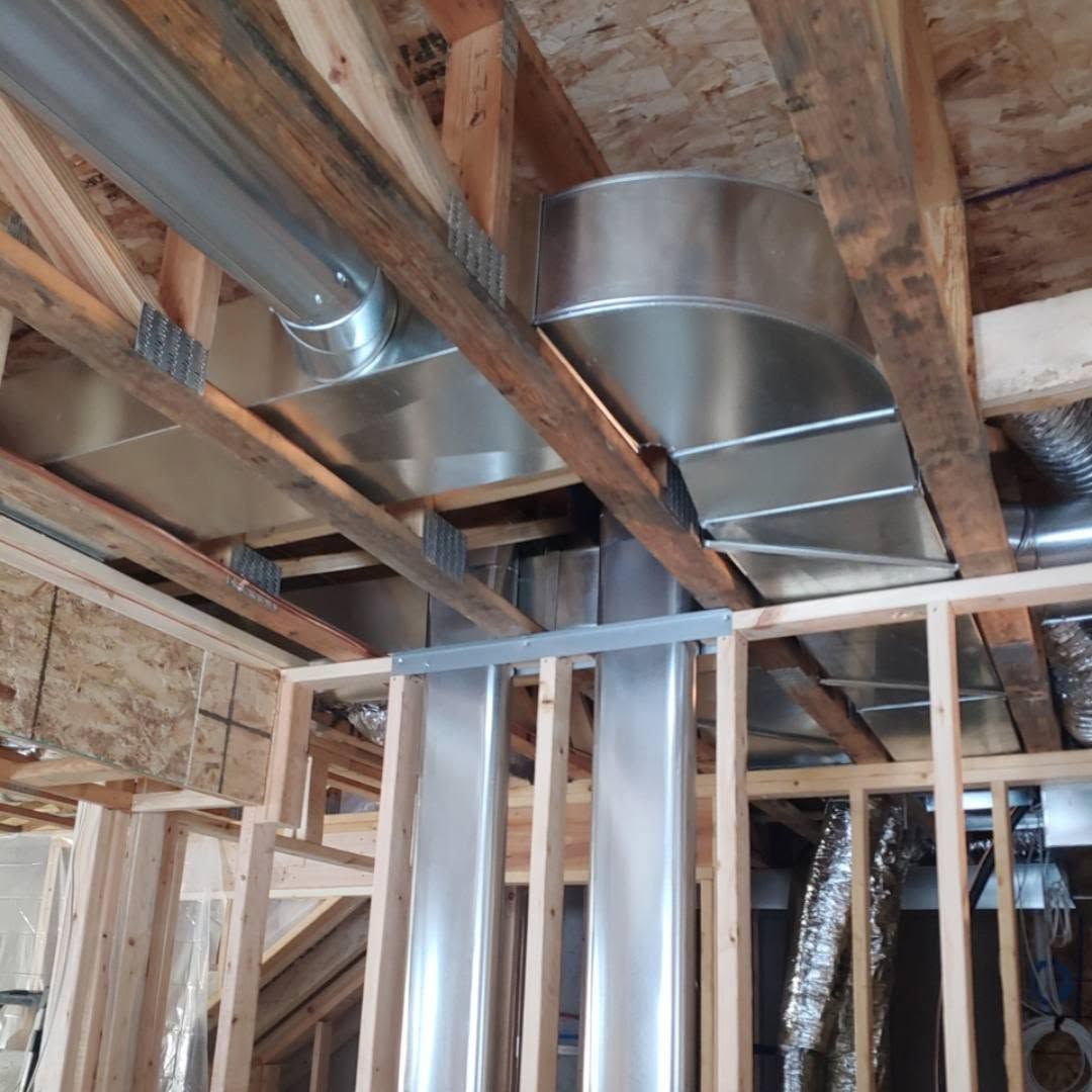 Unfinished attic with exposed wooden framing and shiny metal HVAC ductwork overhead