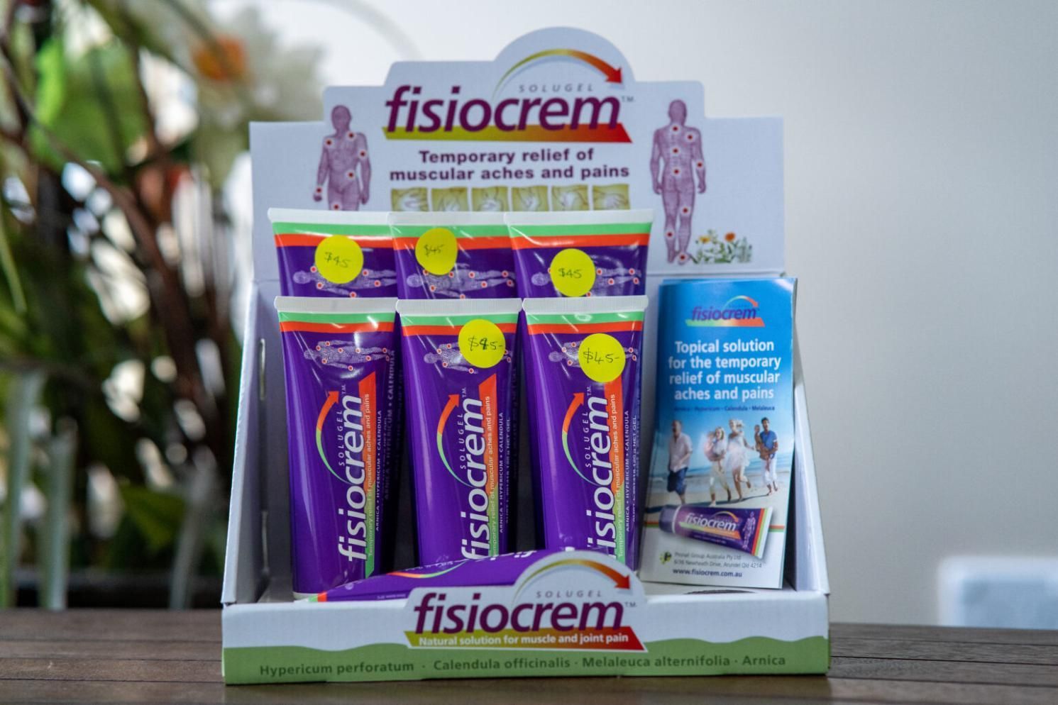 A Display Of Purple Tubes Of Fisiocrem On A Wooden Table — Port Macquarie Physio & Pilates In Port Macquarie, NSW