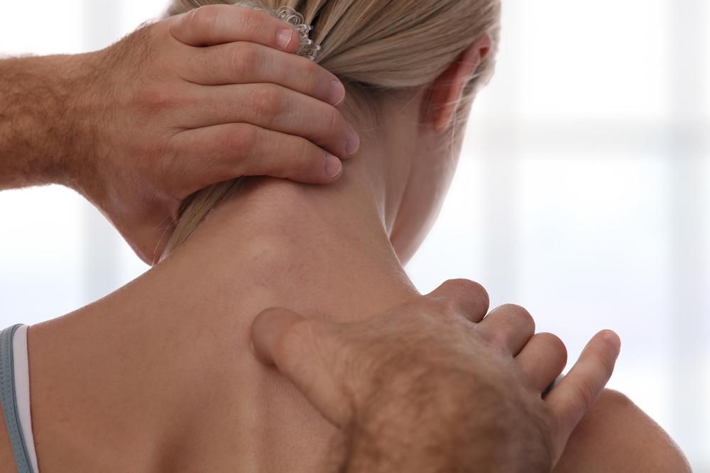 A Man Is Giving A Woman A Neck Massage — Port Macquarie Physio & Pilates In Port Macquarie, NSW