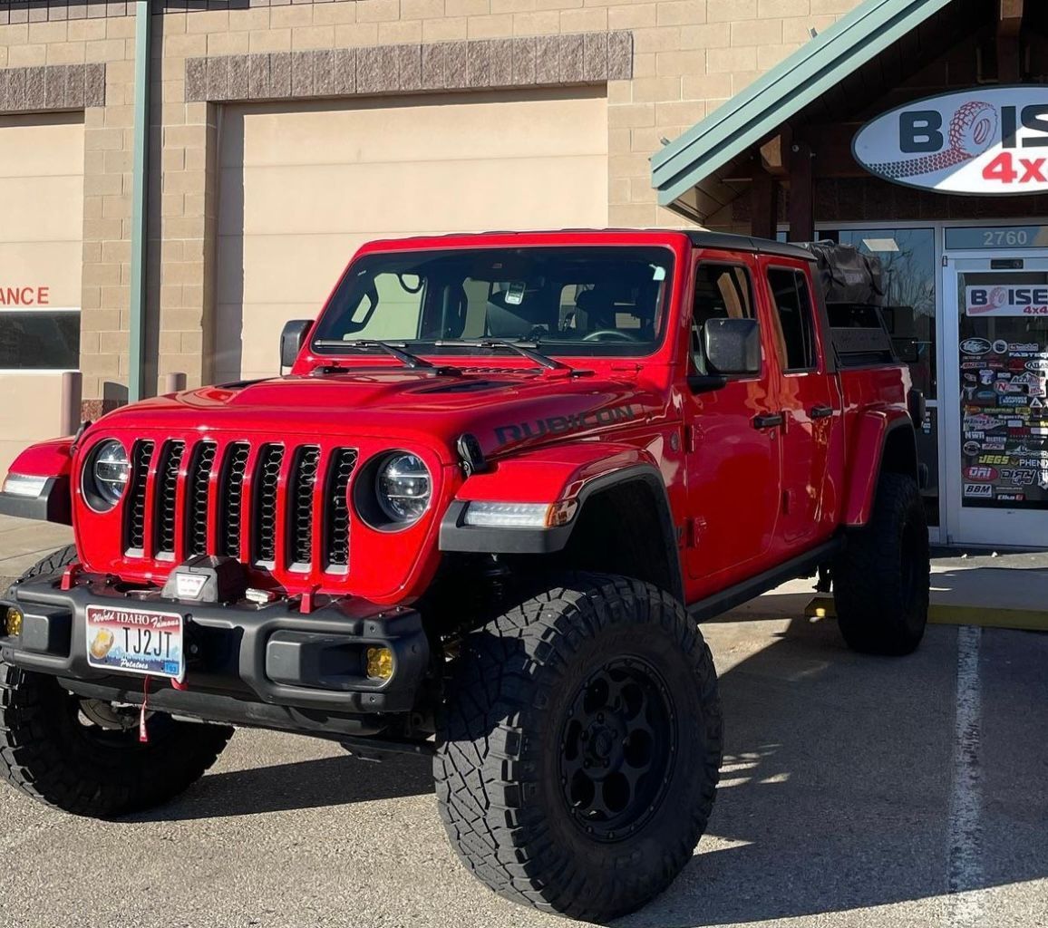 A bright red lifted Jeep Gladiator pickup truck parked in front of a Boise 4x4 shop.