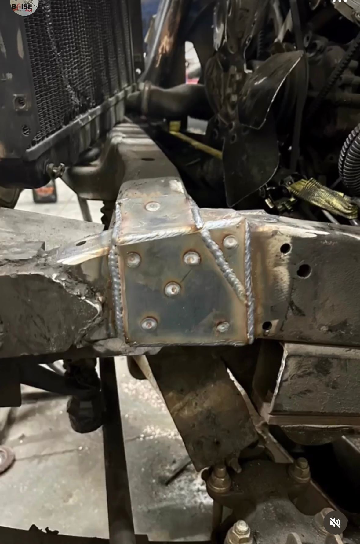 A close-up of a custom metal plate welded onto a vehicle's frame rail during a repair or fabrication project.