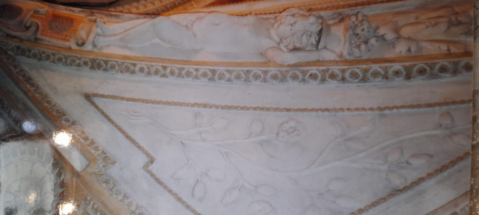 Soffitto bianco decorato con finiture dorate e dettagli in rilievo, probabilmente in un edificio storico.