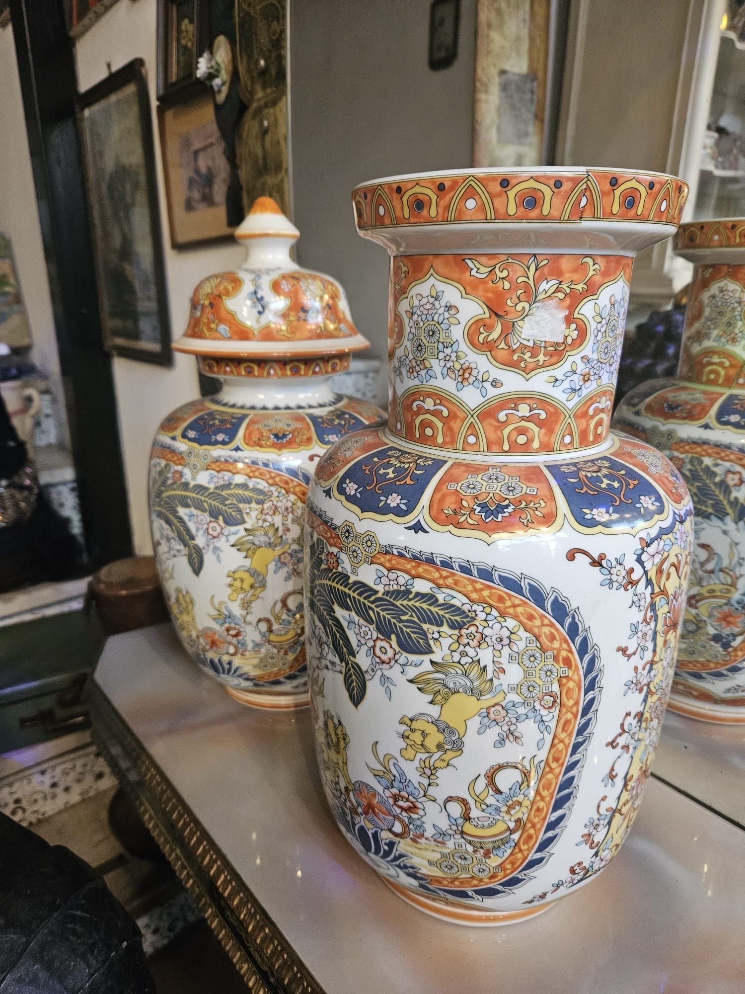 Vasi in ceramica decorati con motivi arancioni, blu e gialli su una superficie a specchio.