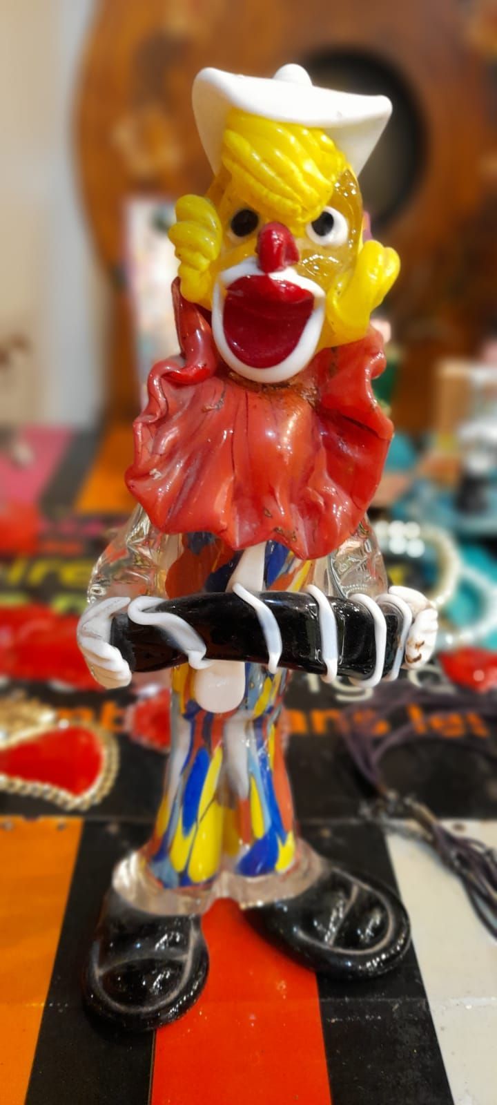 Statuetta di pagliaccio in vetro con gorgiera rossa, capelli gialli e scarpe nere.