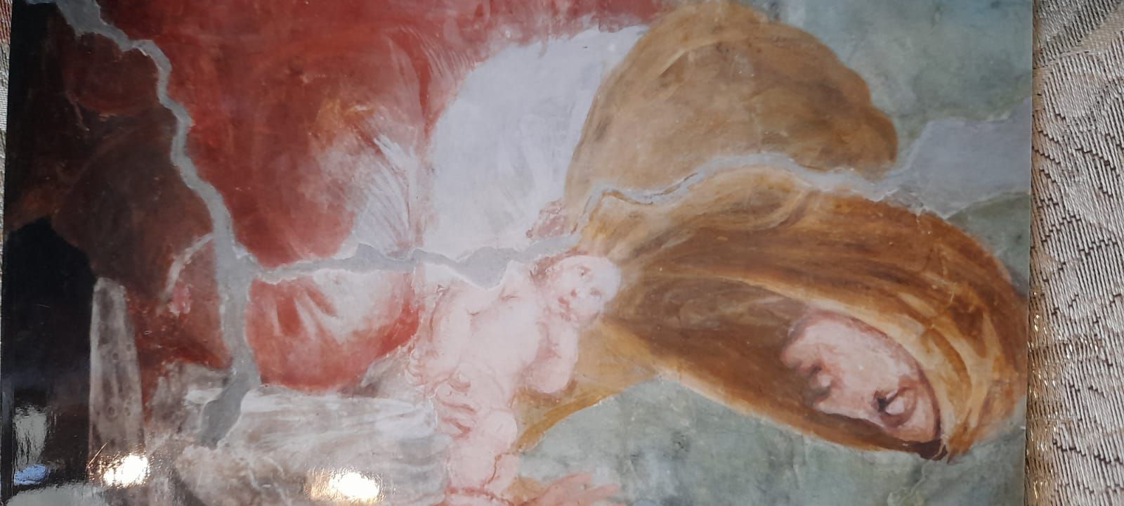 Frammento di affresco raffigurante una persona con lunghi capelli biondi, probabilmente addormentata, e un neonato.