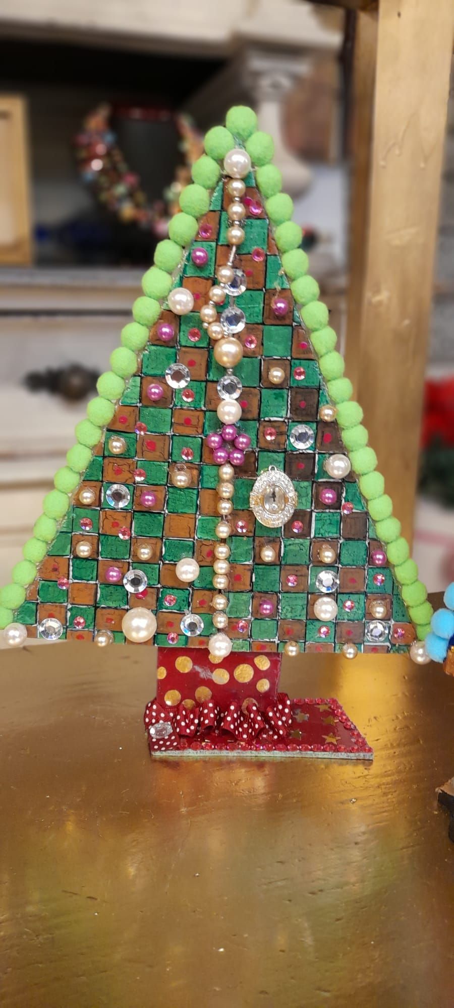 Un albero di Natale decorativo fatto di quadrati e perle. Ha una base rossa con pois bianchi.
