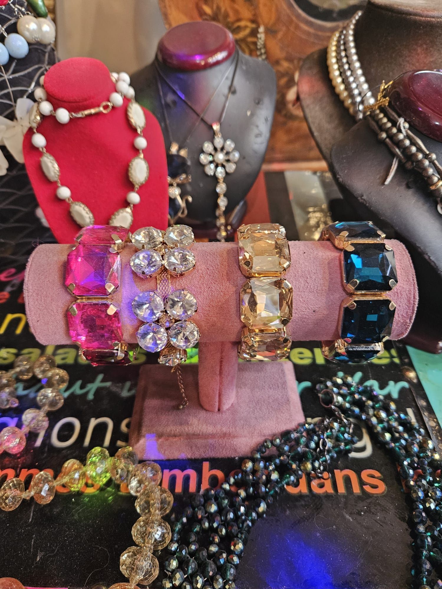Espositore per gioielli con bracciali rosa, trasparenti e blu. Collane di perle e cristalli.