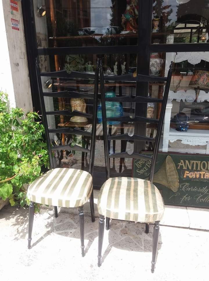 Due sedie nere con la seduta a strisce esposte fuori da un negozio.