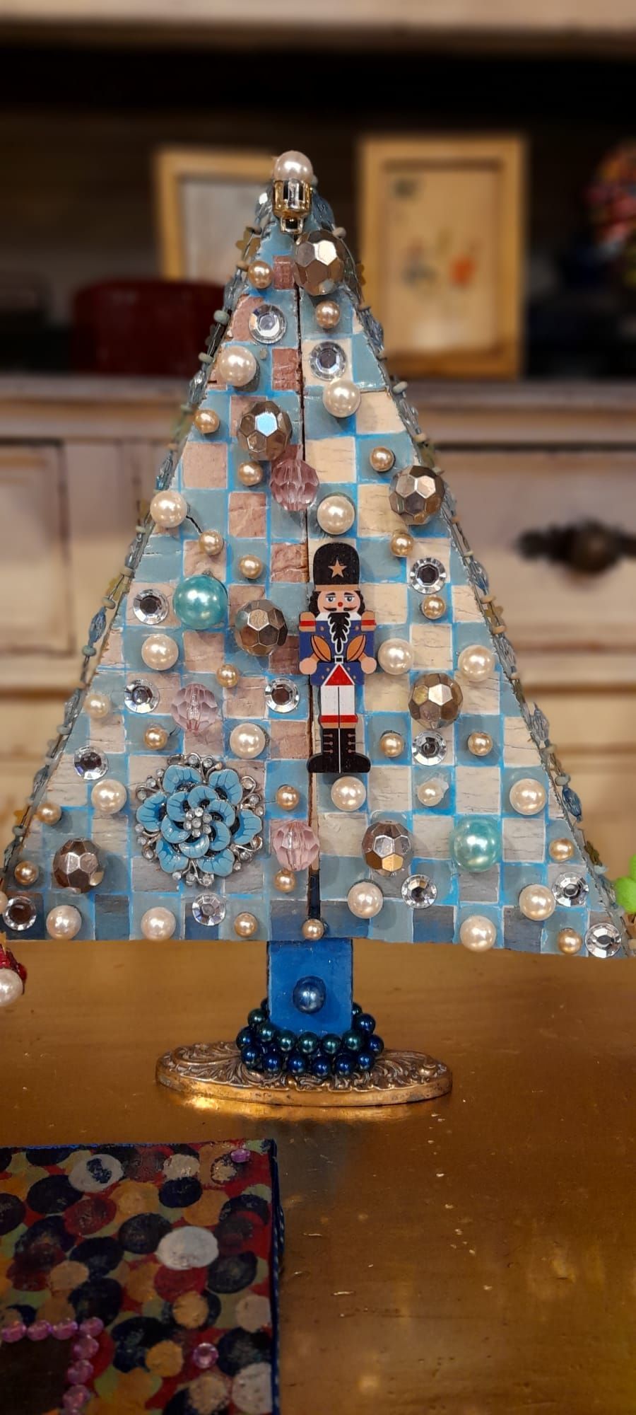 Albero di Natale blu decorato con schiaccianoci, perle e gioielli, sul tavolo.