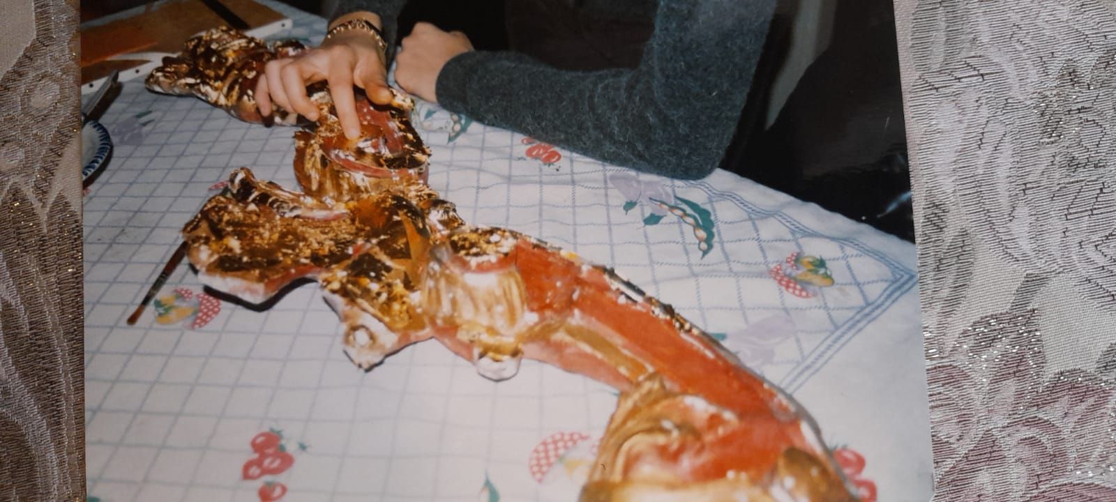 Persona che tocca un oggetto ricoperto d'oro su una tovaglia a quadri.