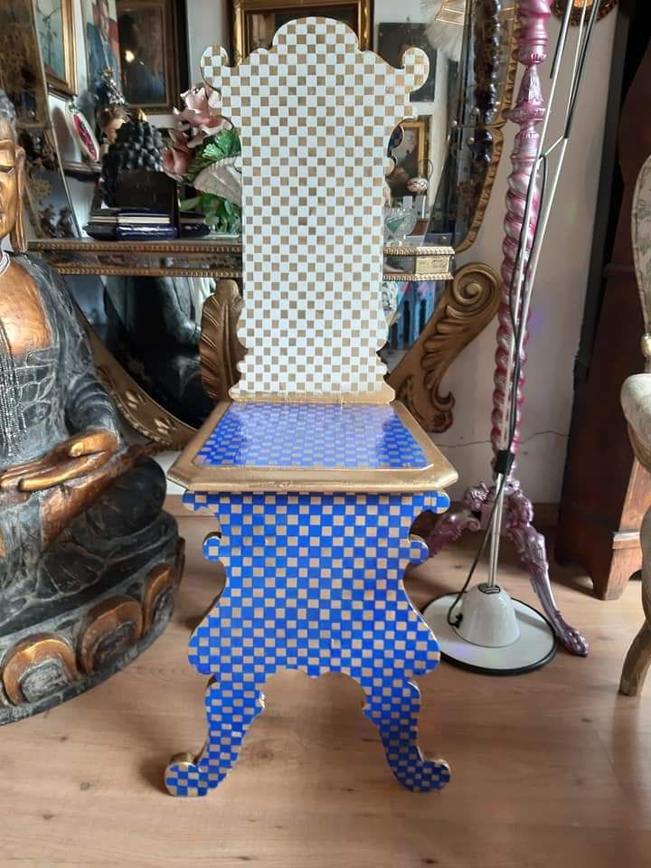 Sedia a scacchiera blu e bianca con finiture dorate, design elaborato, ambiente interno.