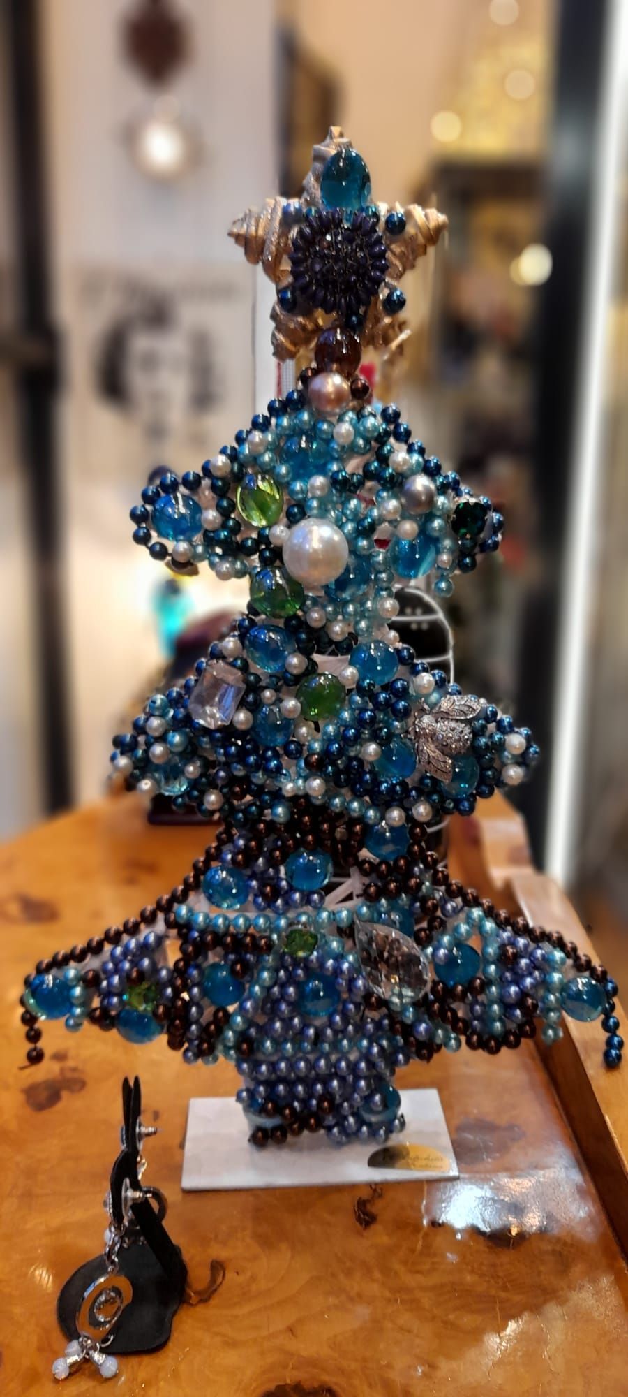 Albero di Natale con perline, dettagli blu e bianchi, puntale a forma di stella, su una superficie di legno.