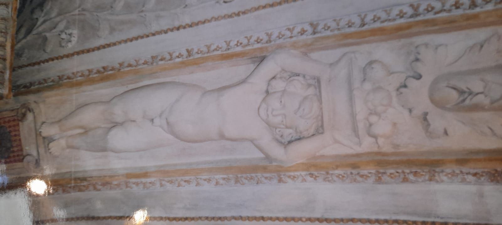 Una figura scolpita sdraiata con le braccia sopra la testa, scolpita in una parete.