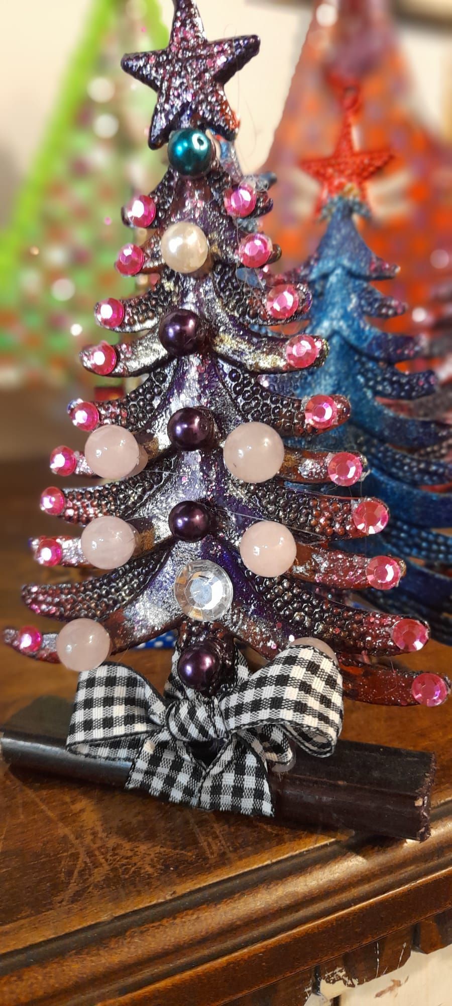 Albero di Natale scintillante con decorazioni e un fiocco a quadretti su un tavolo.