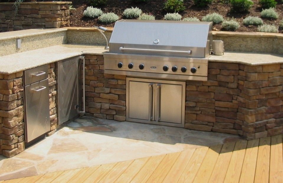 Outdoor stainless steel grill and stone kitchen on a wooden deck with built-in cabinets