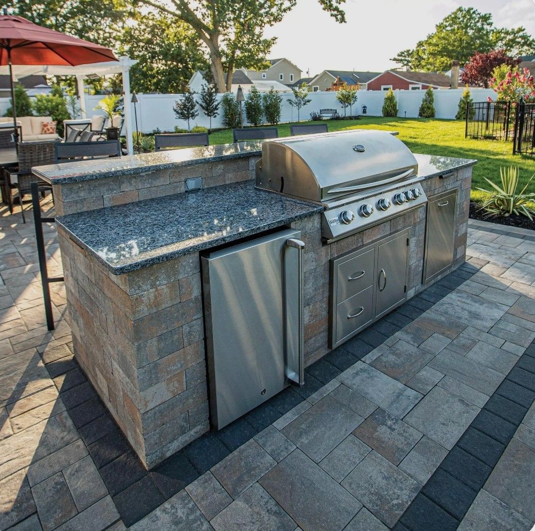 Outdoor stone barbecue grill with granite counter in a landscaped backyard patio