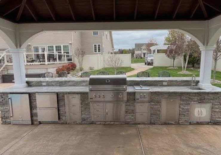 Long outdoor concrete table with benches in a park or patio, beside a lawn and trees