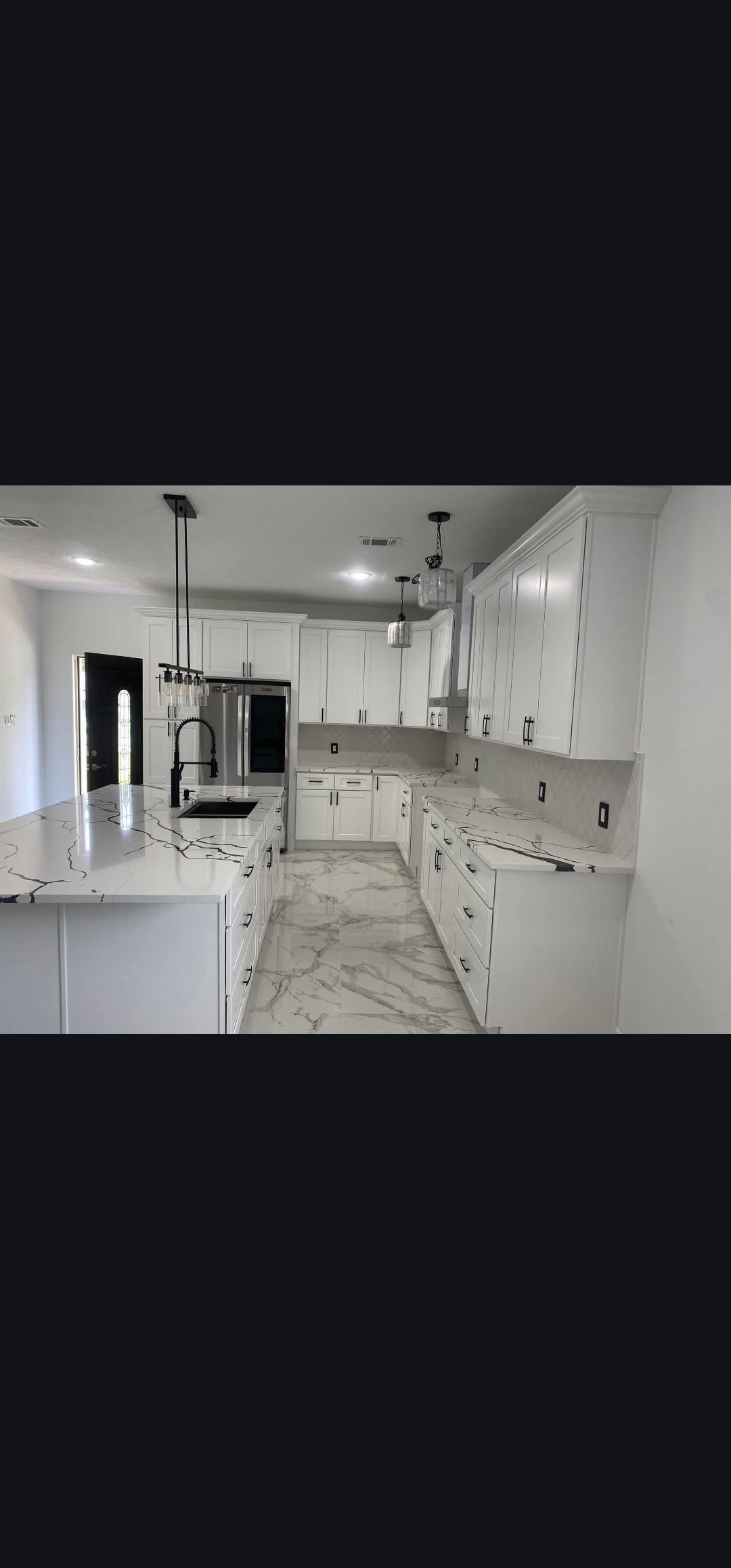 Bright white kitchen with cabinets, island, and marble-pattern floor, seen in a modern interior.