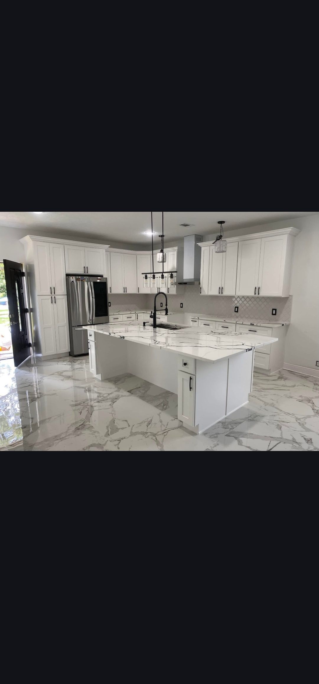 Bright modern kitchen with white cabinets, large island, and pendant lights in an open-plan home.