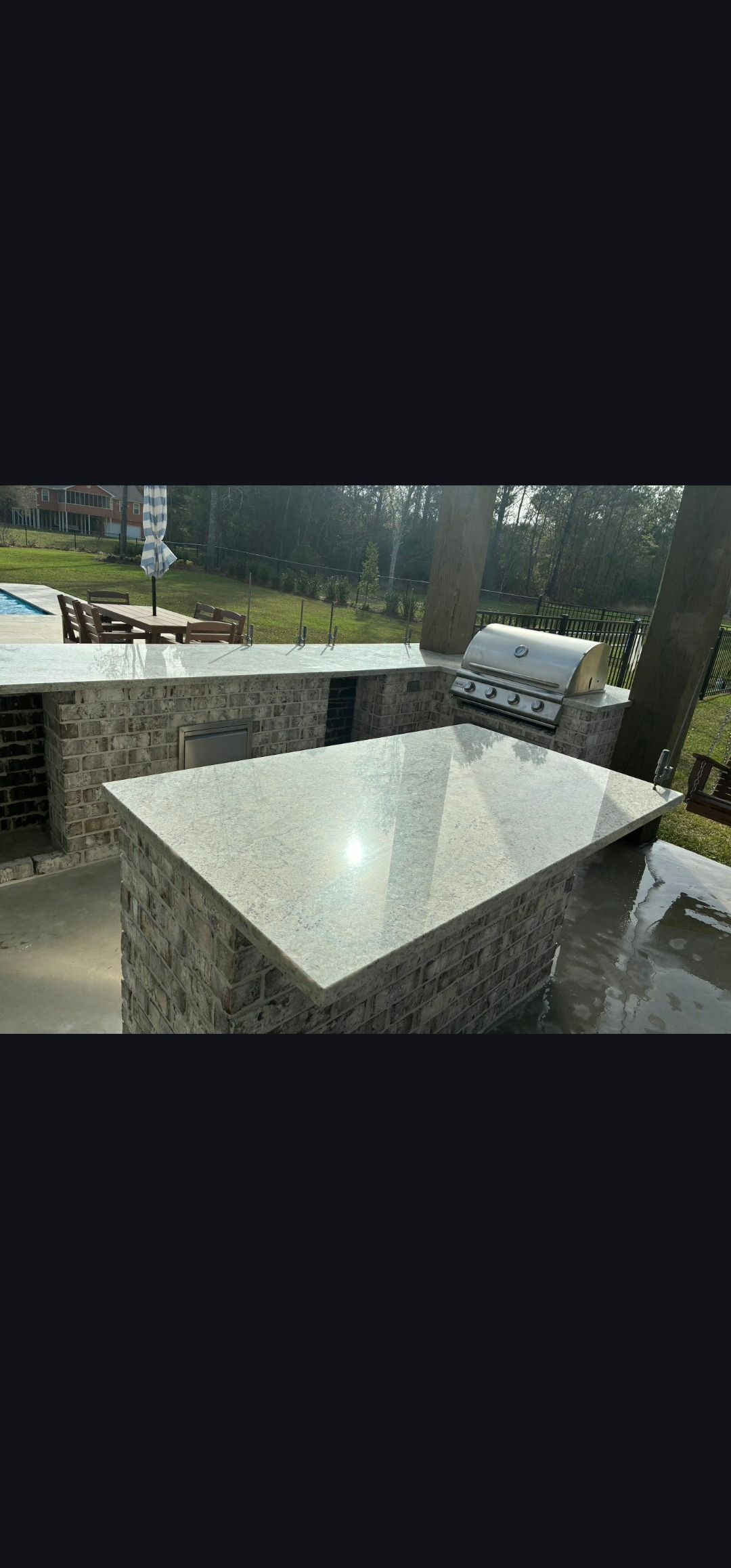 Rainy patio with stone table and bench seating overlooking a wet outdoor area