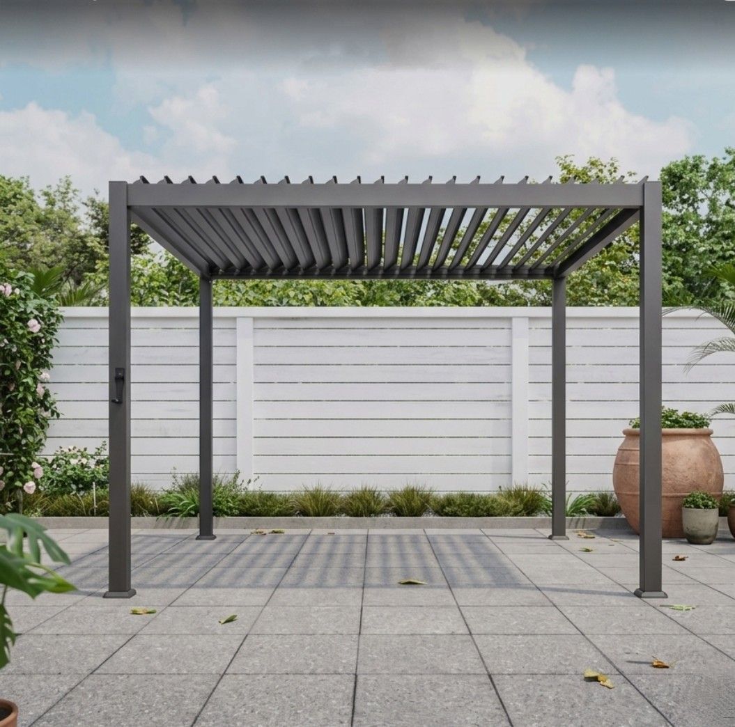 Modern gray pergola on a paved patio beside a white privacy fence and potted plants.