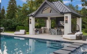 Backyard stone patio with a circular fire pit and garage in the background