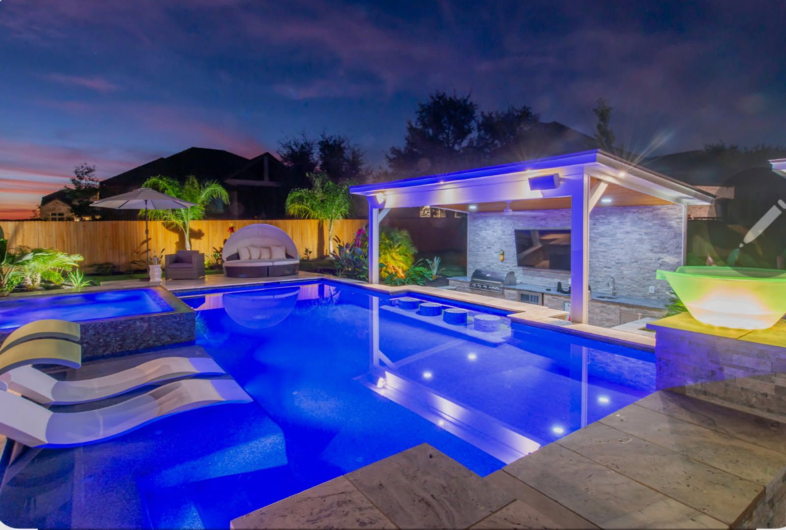 Night-lit landscaped garden with ornamental grasses and glowing path lights beside a house
