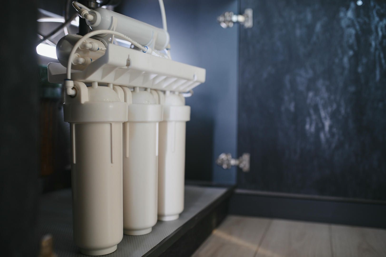 A water filter is sitting under a sink in a bathroom.