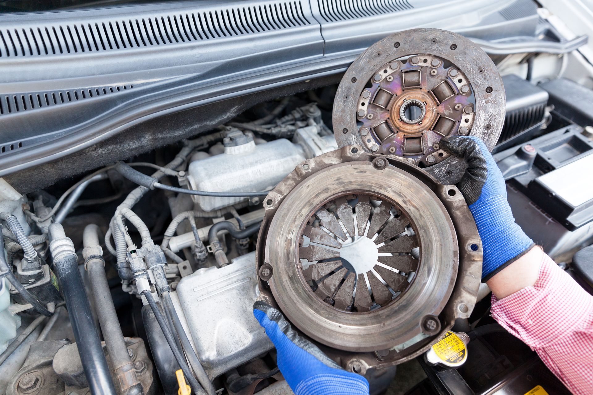 Close-up of a used clutch disc and pressure plate for a professional auto clutch replacement. Close-up of a used clutch disc and pressure plate for a professional auto clutch replacement.