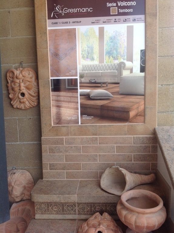 Esposizione di piastrelle decorative per pavimenti e rivestimenti con elementi in ceramica in una vetrina di uno showroom.