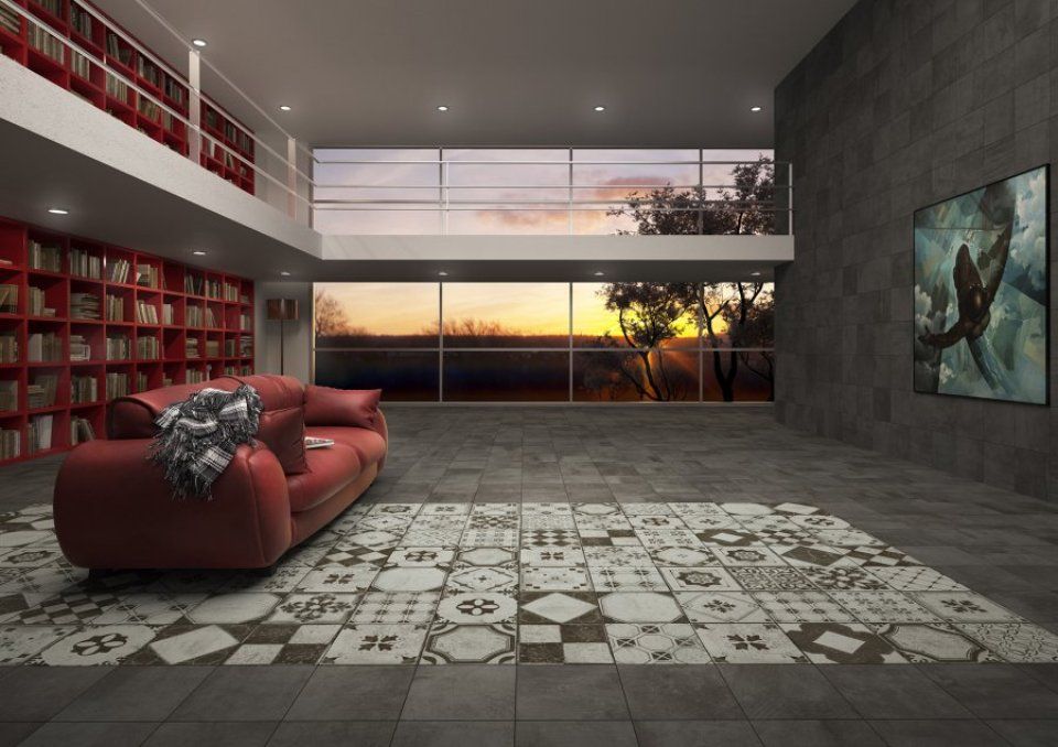 Soggiorno moderno con divano rosso, tappeto a motivi geometrici, parete con libreria e vista del tramonto attraverso ampie finestre.