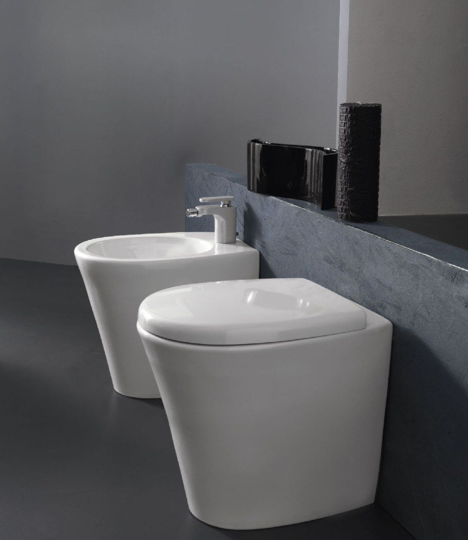 Due moderni WC bianchi accanto a una parete grigia in un bagno minimalista