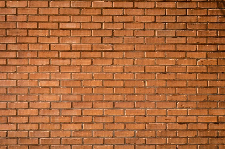 Muro in mattoni rossi con fughe orizzontali di malta e una texture leggermente usurata.