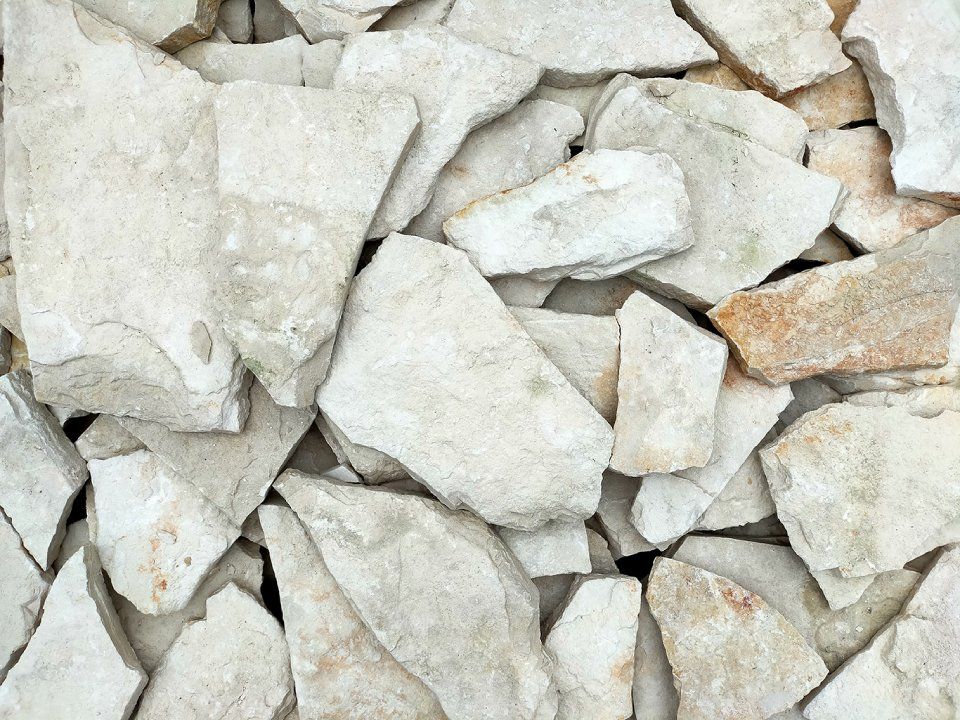 Cumulo di frammenti di pietra bianca e beige, rotti e dai bordi ruvidi e frastagliati.