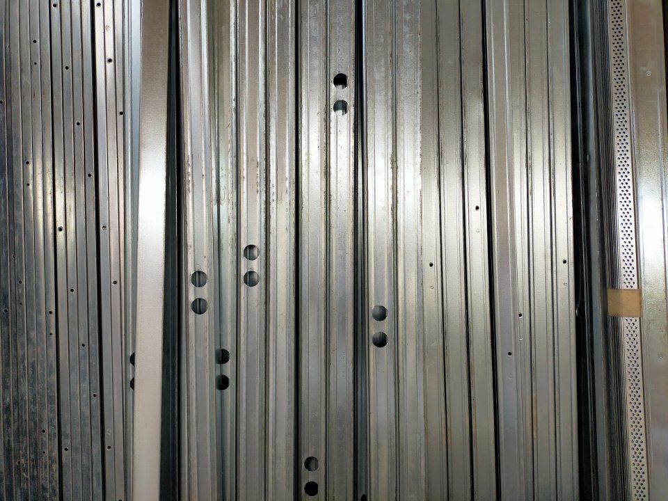Pannelli verticali in metallo argentato con file di rivetti e fori neri