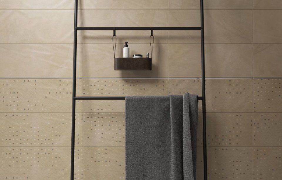 Mensola da bagno con asciugamani grigi e articoli da toeletta su una parete piastrellata beige.