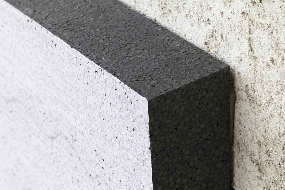 Primo piano di un angolo di cemento grigio su uno sfondo di muro bianco e punteggiato.