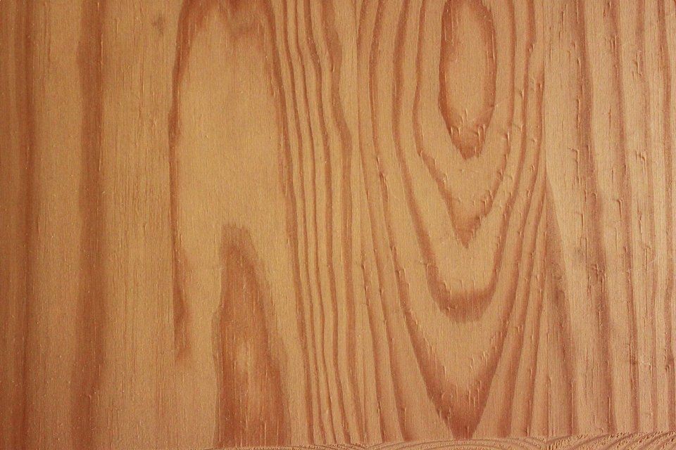 Primo piano di venature del legno marrone chiaro con motivi verticali ondulati.