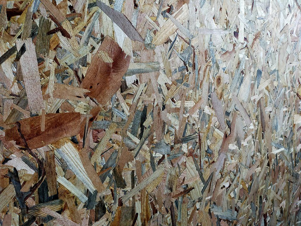 Primo piano di schegge e frammenti di legno grezzo nei toni del beige, del marrone e del grigio.