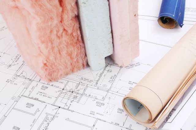 Progetto con campioni di materiale isolante e planimetrie arrotolate su un tavolo