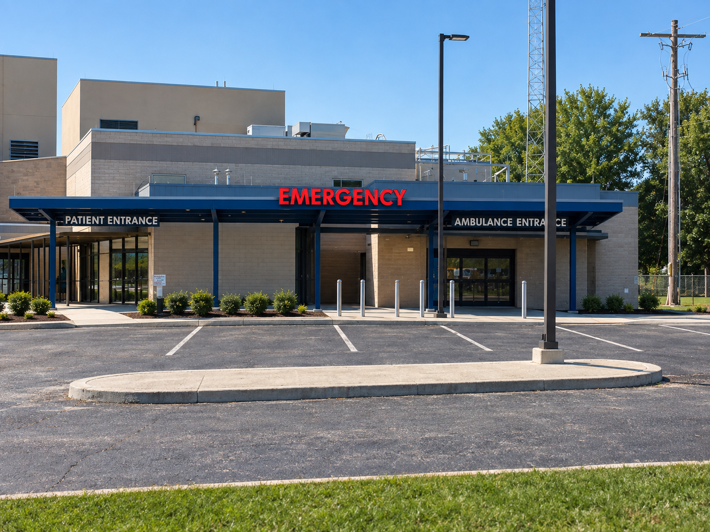 Hospital emergency entrance with red ER sign, glass doors, and empty parking area on a sunny day